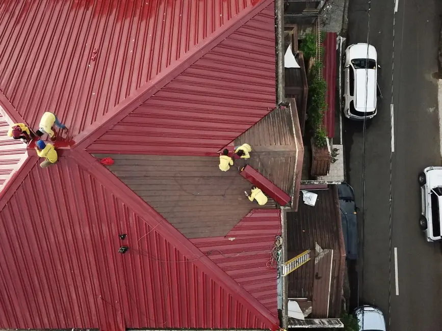 Aerial view of workers repairing a red metal roof in Quezon City, Philippines.
