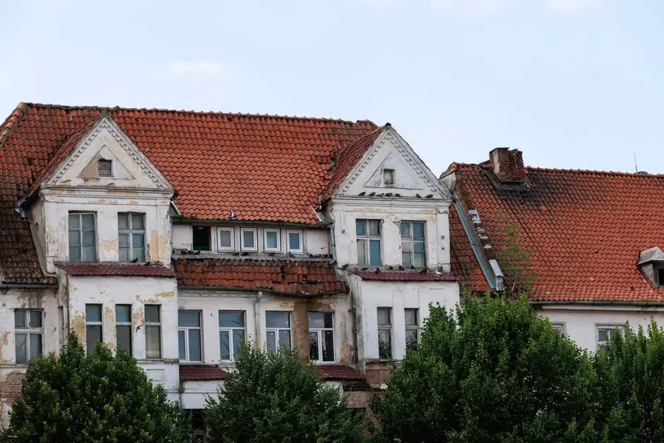 Aged building with red tiled roofs showcasing classic European architecture amid lush greenery.